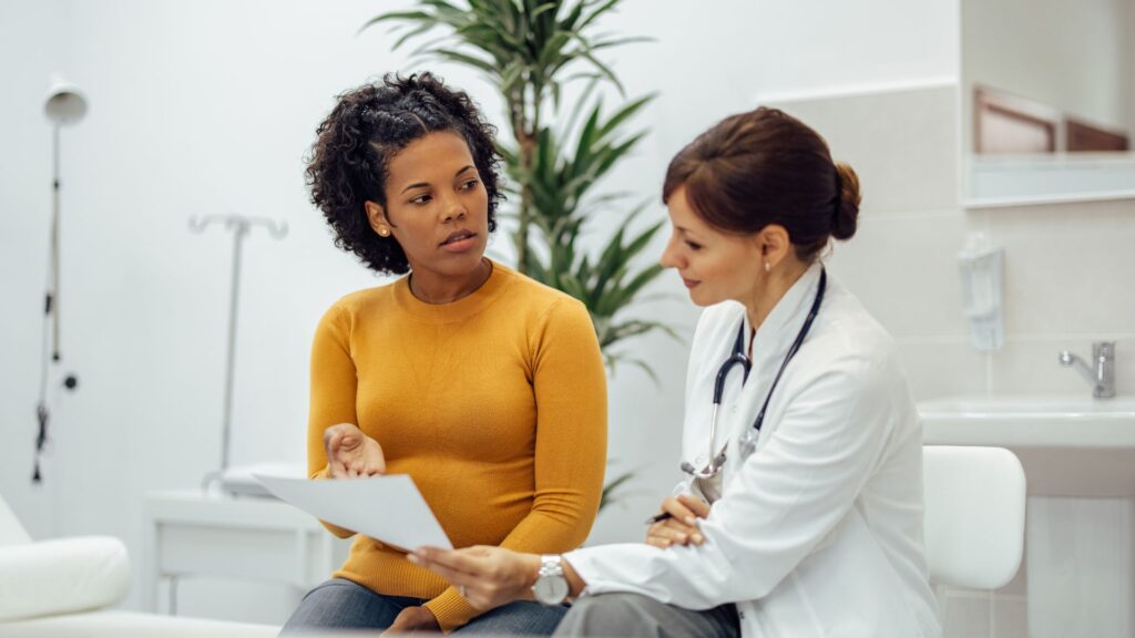 Female doctor discussing treatment options with a woman during a medical consultation about menopausal care after early menopause or cancer.