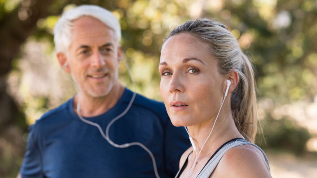 Middle-aged couple outdoors in activewear, listening and supporting each other during a walk, representing how to support your partner through menopause.