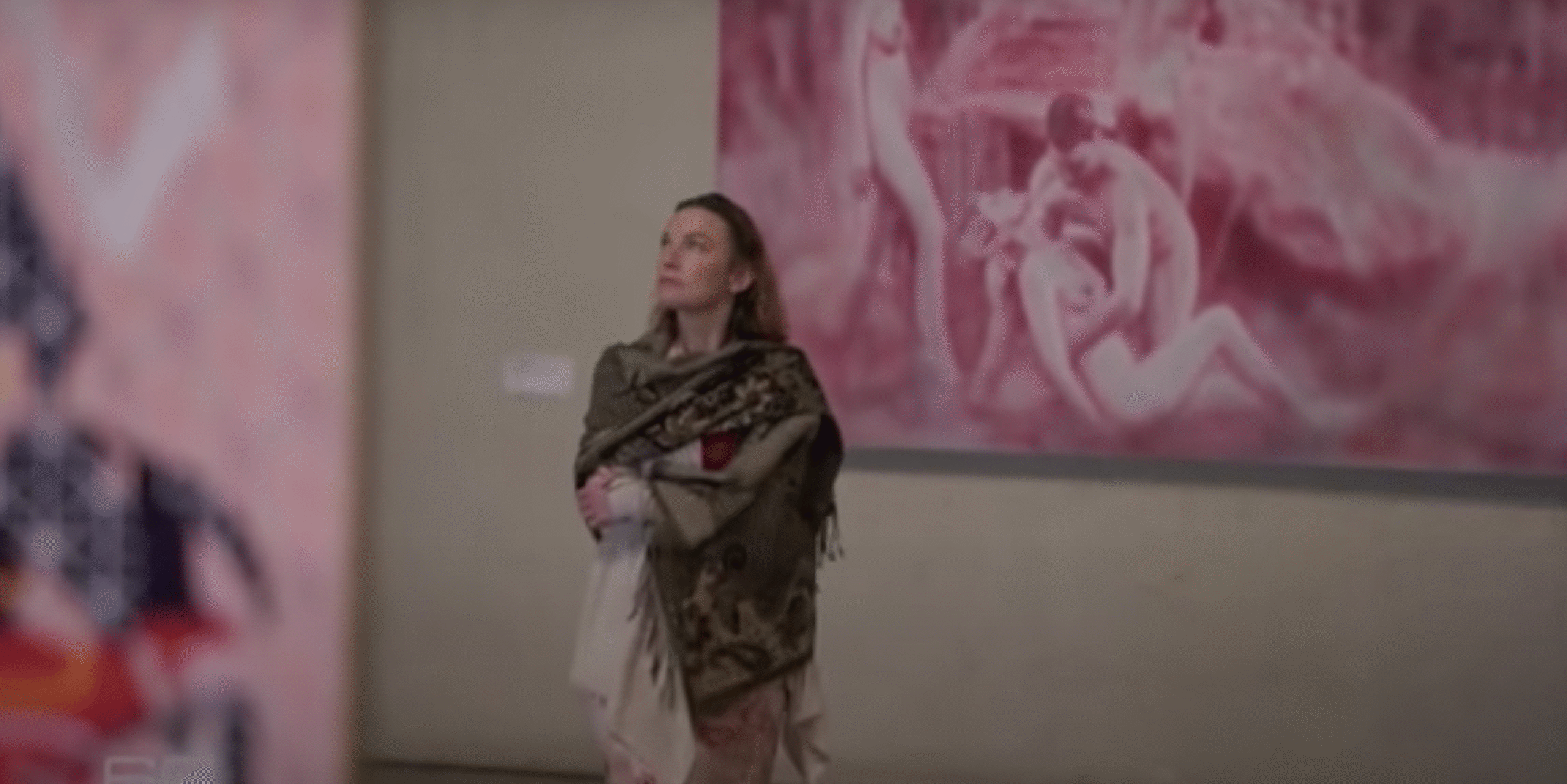 Woman standing in an art gallery with folded arms in front of a large pink artwork, reflecting on a personal “60 Minutes of Fame” moment.