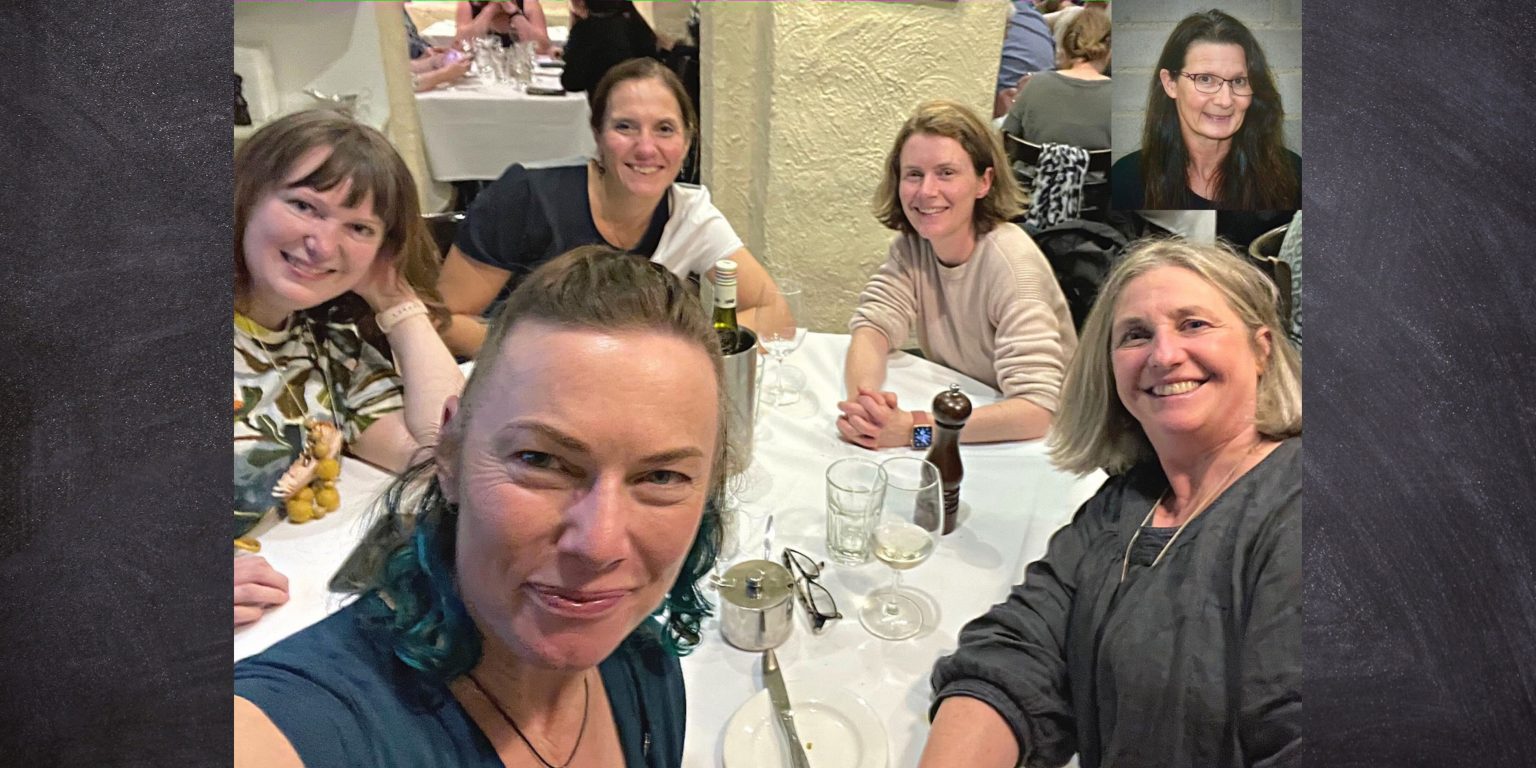 Group of women smiling at a dinner table during the AMS Congress, sharing the latest menopause updates.