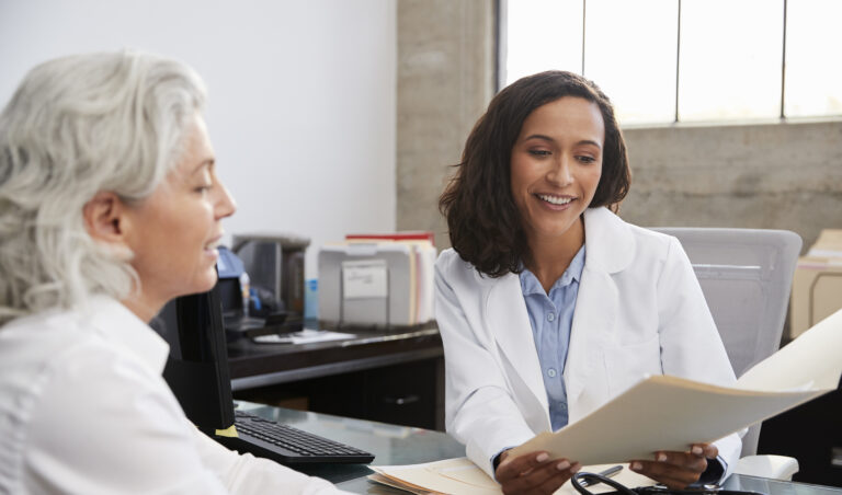 Female GP reviewing paperwork with a patient during a consultation about menopausal hormone therapy.