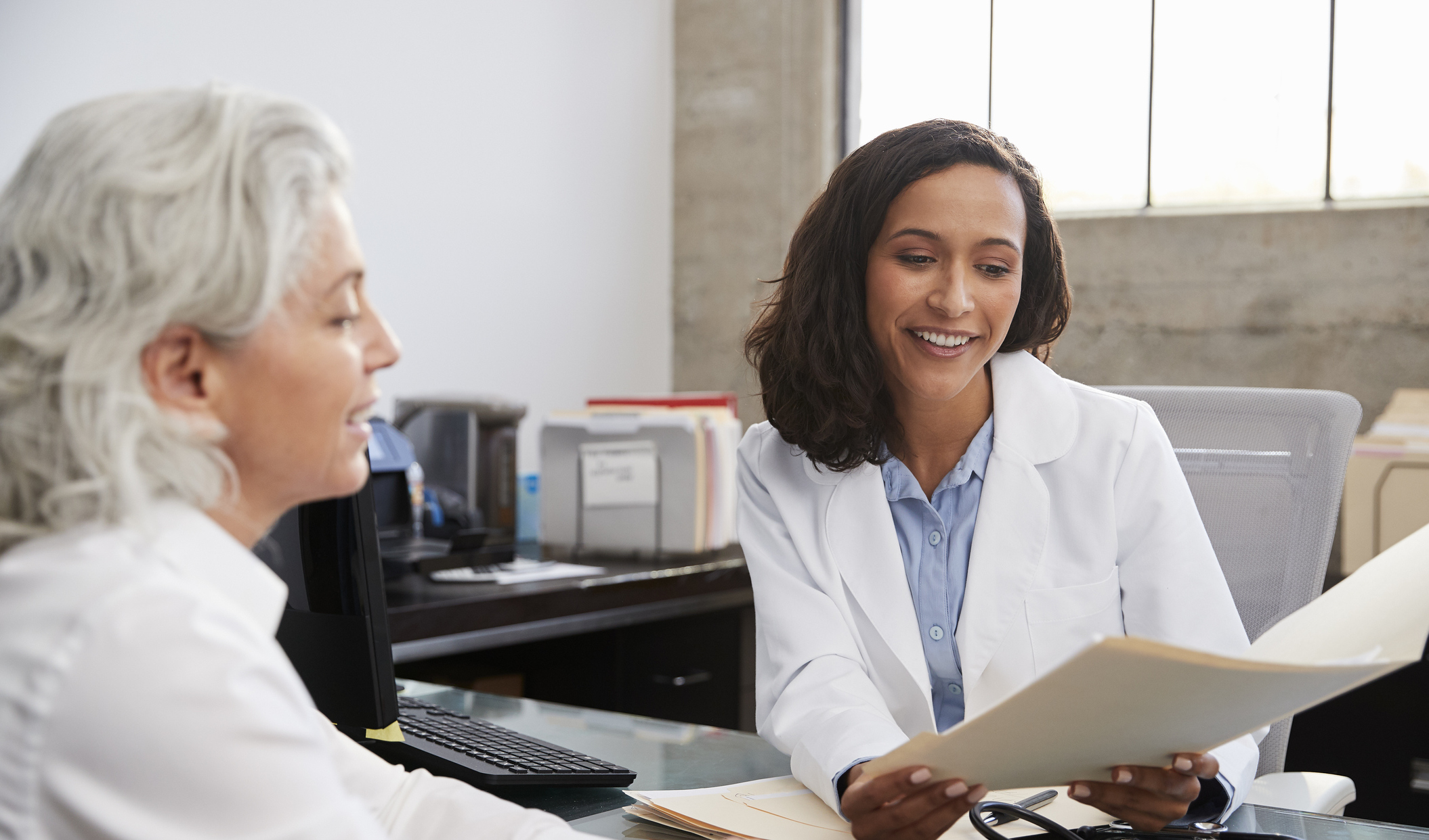 Female GP reviewing paperwork with a patient during a consultation about menopausal hormone therapy.