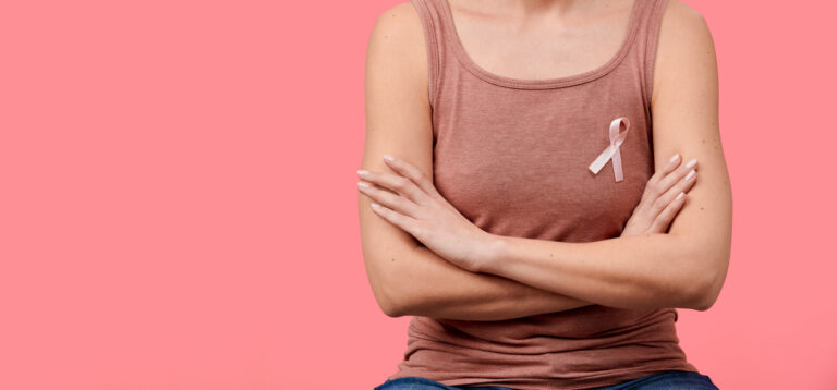 Woman wearing a pink top with a breast cancer awareness ribbon, representing concerns about hormonal therapy and breast cancer risk.