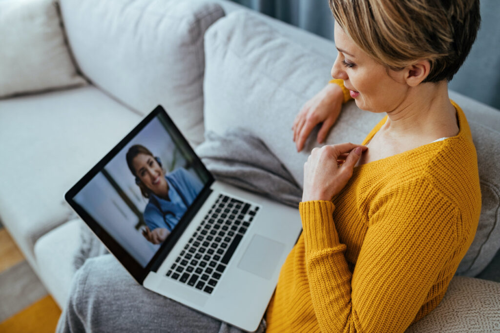 Woman having an online video consultation with a doctor on her laptop, highlighting the importance of regular medical reviews during menopause.